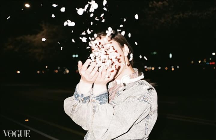 PhotoVogue image of a person tossing white petals at night