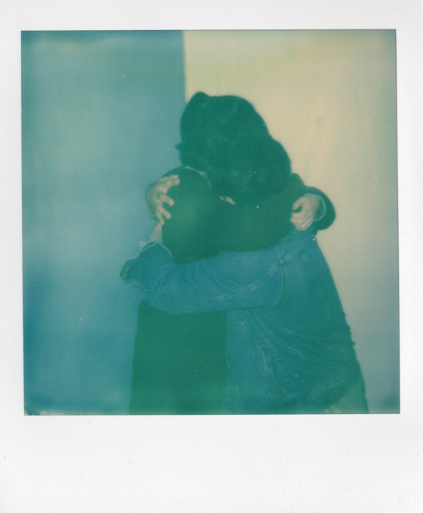Polaroid of an embrace in a blue-green cast