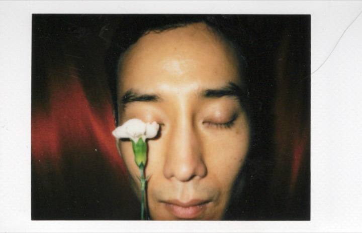 Male portrait with a flower near a closed eye