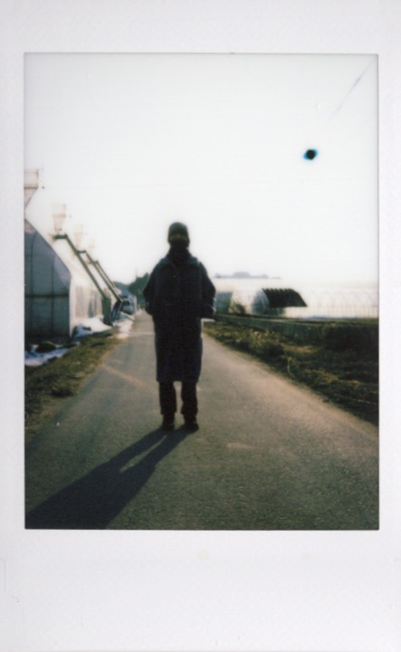 Backlit figure standing alone on a road