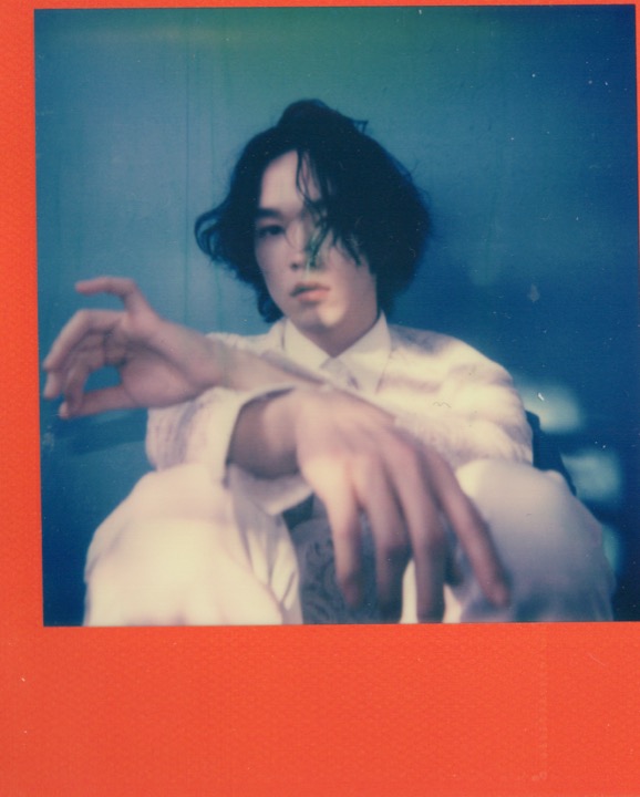 Seated portrait with arms reaching toward the frame