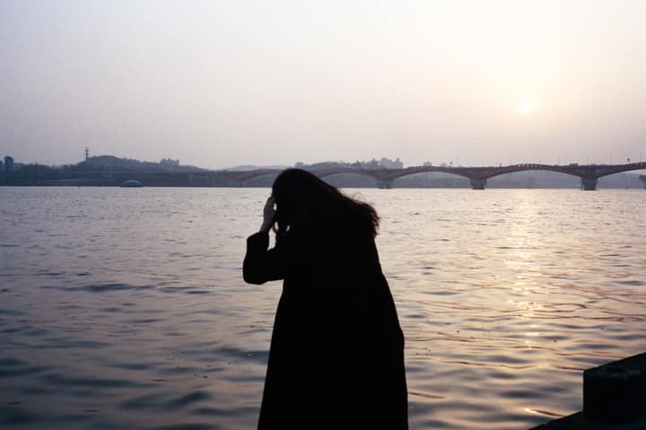 Silhouetted figure photographing the river at sunset