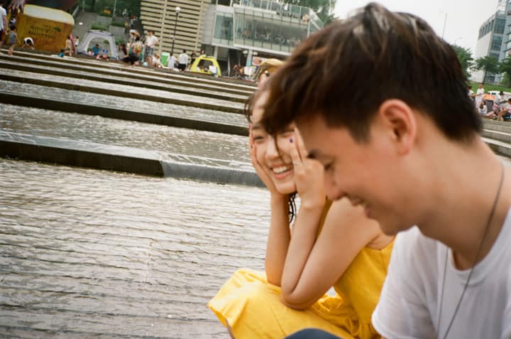 Two people laughing beside a river in Seoul