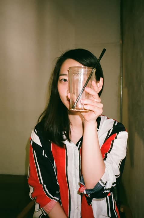 Portrait of a woman holding a glass object over one eye
