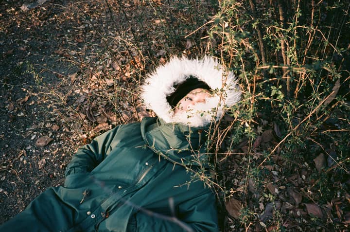 Person lying on the ground in a green coat