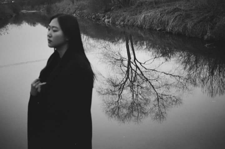 Black-and-white profile portrait reflected near water
