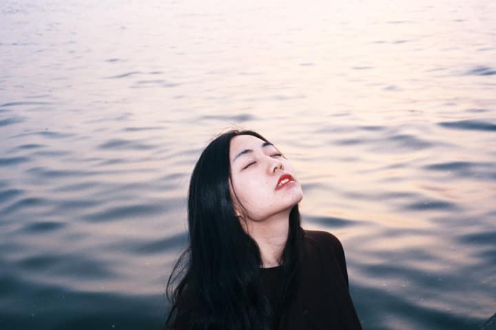 Close portrait of a woman with eyes closed near water