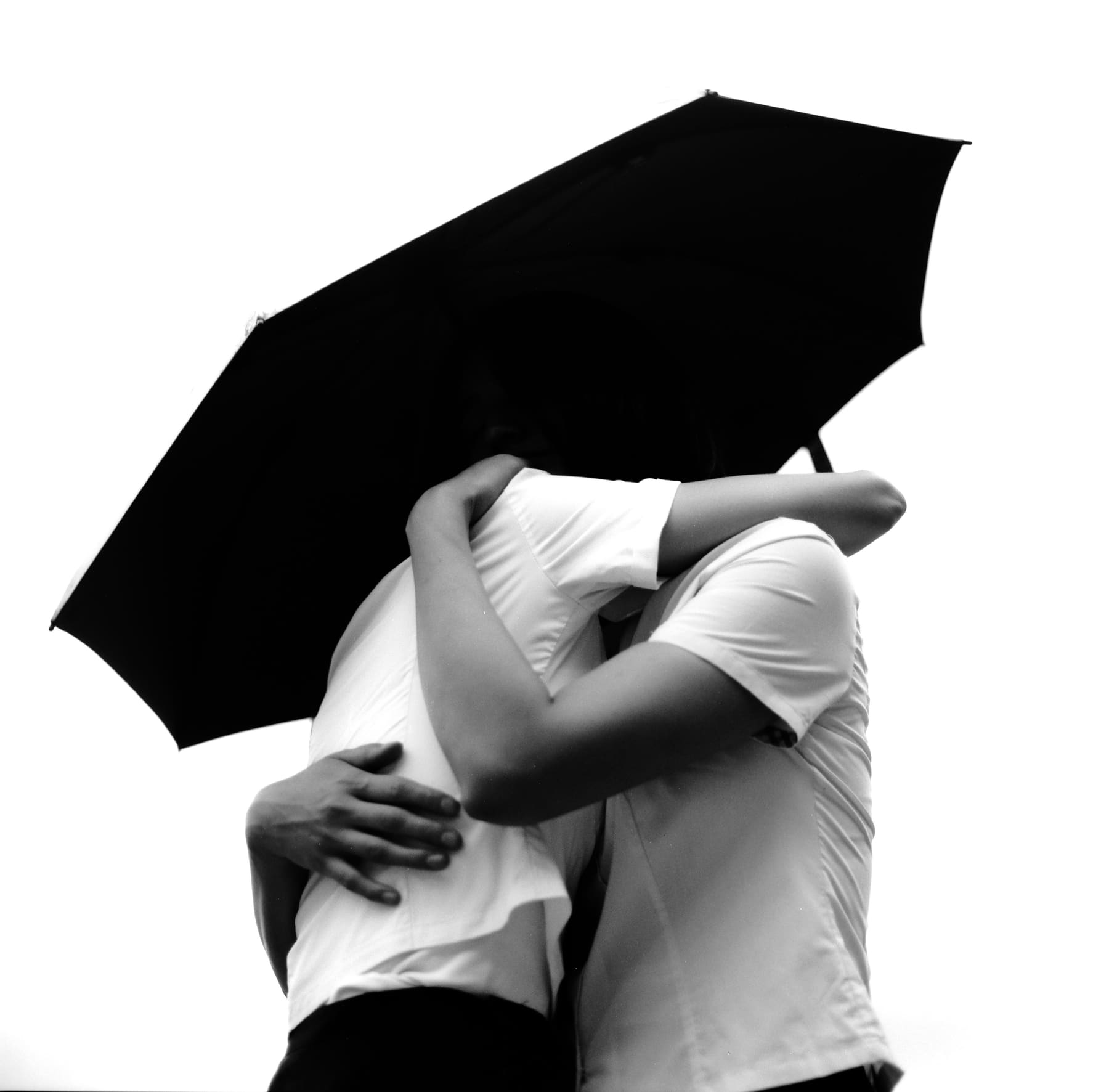 Black-and-white portrait of two women embracing under an umbrella